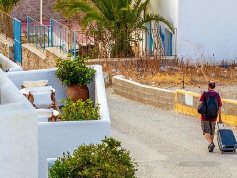 Άνδρας περπατάει με βαλίτσα στο χέρι σε νησί