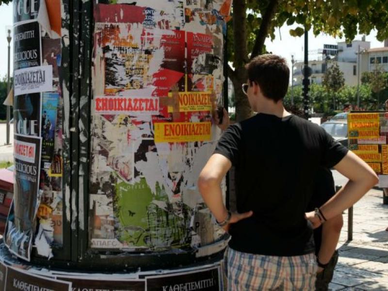 φοιτητής ψάχνει για σπίτι κοιτώντας αγγελίες στο δρόμο