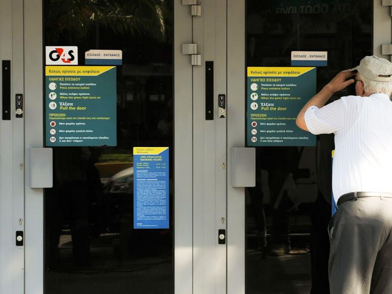 Συνταξιούχος σε τράπεζα κοιτάει μέσα από το τζάμι